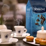 Borbone Caffè kava u keramičkim šalicama s pakiranjem kave i kolačićima na stolu