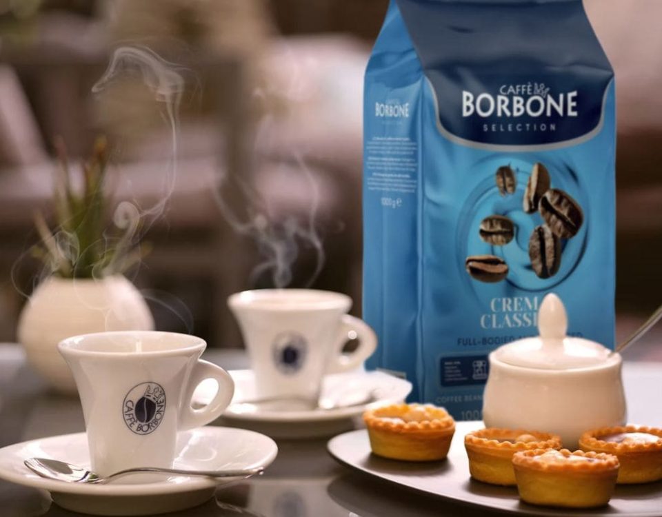 Borbone Caffè kava u keramičkim šalicama s pakiranjem kave i kolačićima na stolu