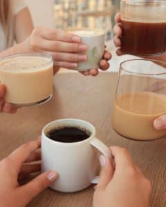 Grupica prijatelja nazdravlja kavom posluženom u raznim šalicama – crna, mliječna i pjenasta kava