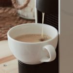 Bijela šalica ispod kapsula aparata dok se priprema espresso kava