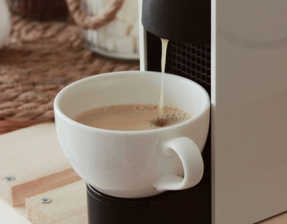 Bijela šalica ispod kapsula aparata dok se priprema espresso kava