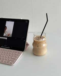 Tablet s tipkovnicom i ledena kava na bijelom stolu.